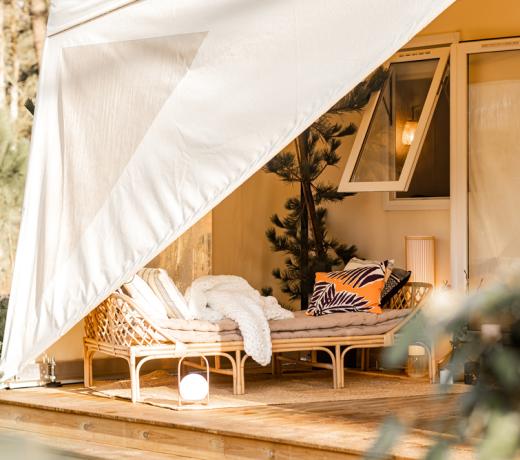 Accogliente veranda con divano in vimini e cuscini colorati, immersa nella natura.
