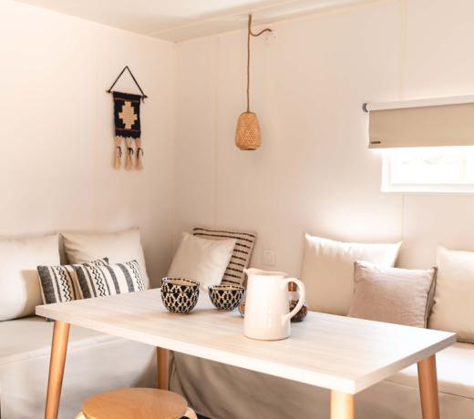 Interno accogliente con tavolo, cuscini e decorazioni minimaliste.