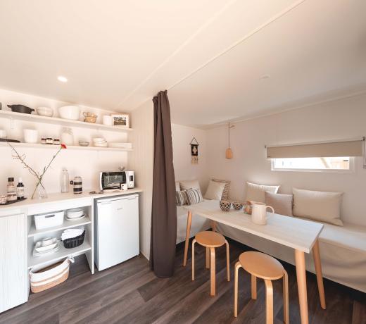 Piccola cucina minimalista con tavolo e sedie in legno chiaro.