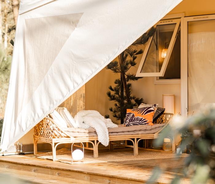 Accogliente veranda con divano in vimini e cuscini colorati, immersa nella natura.