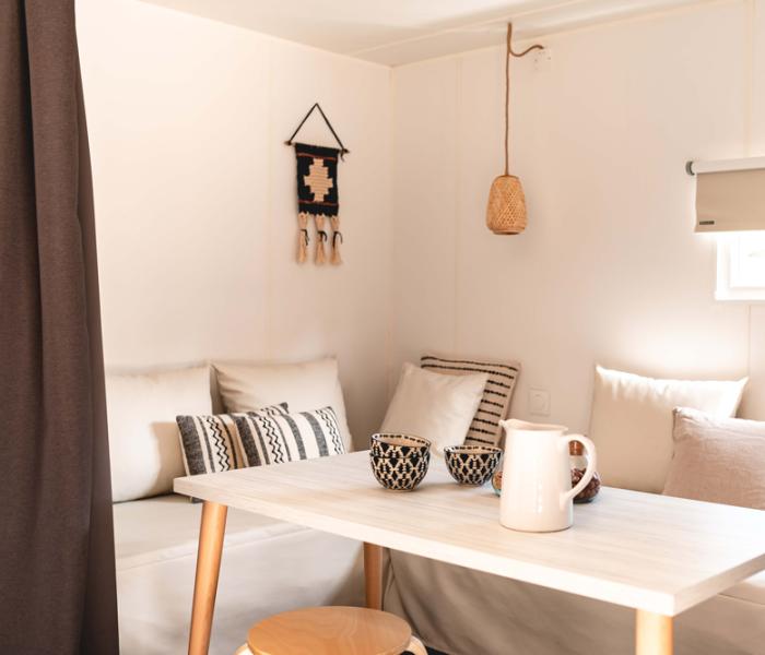 Interno accogliente con tavolo, cuscini e decorazioni minimaliste.
