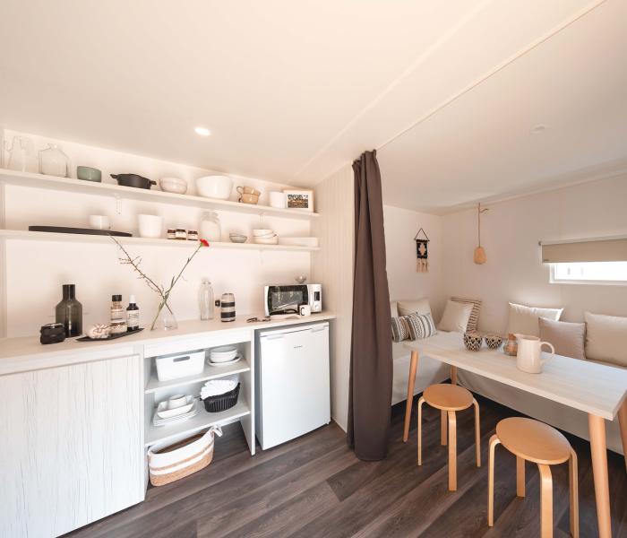 Piccola cucina minimalista con tavolo e sedie in legno chiaro.